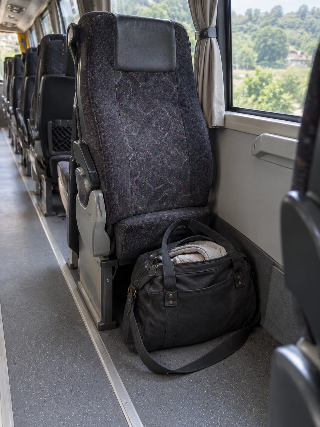 A compact overnight bag on the floor beside an ordinary intercity coach seat.